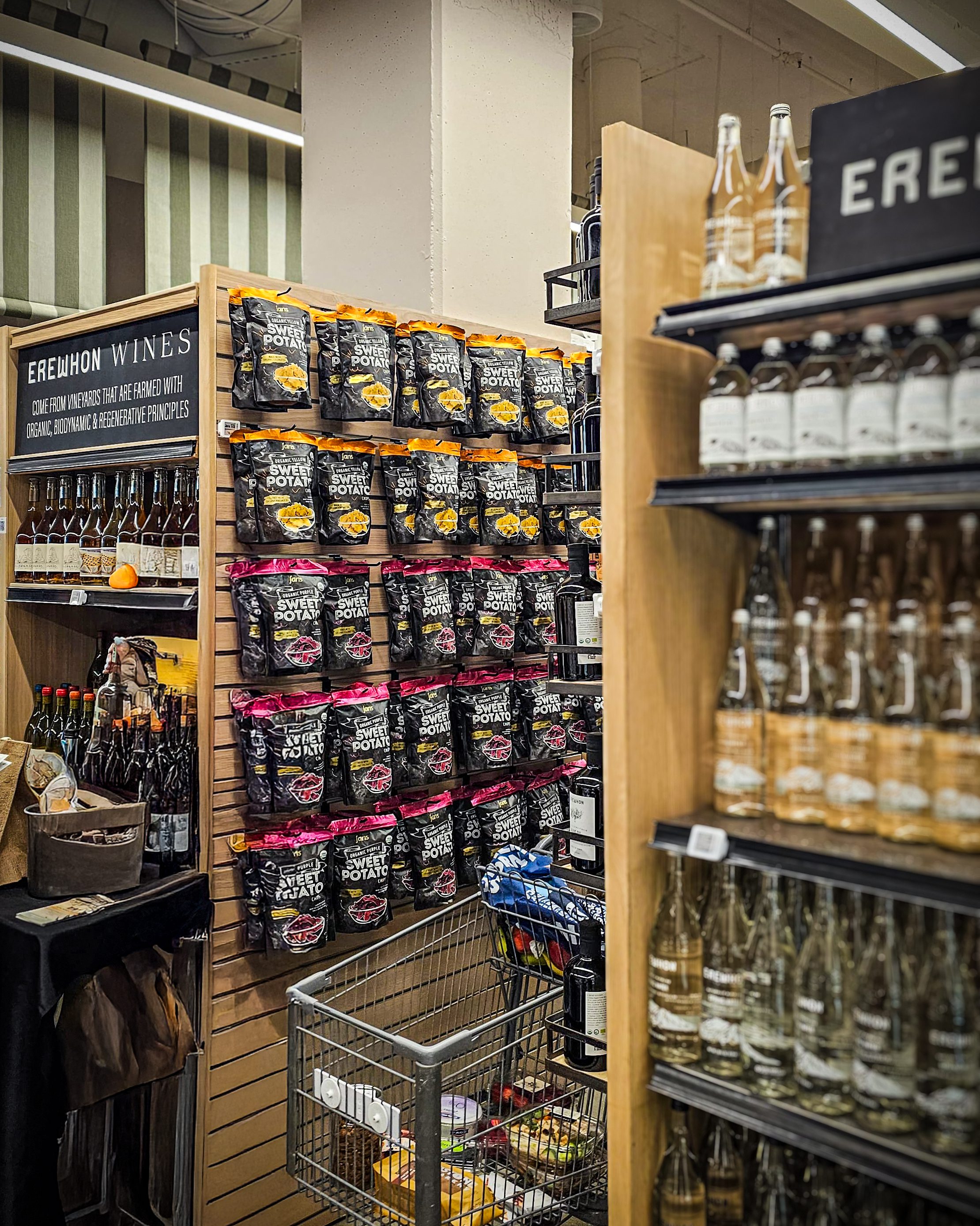 Display of Jans Organic Purple and Yellow Sweet Potato Chips on shelves at Erewhon Market Beverly Hills, next to Erewhon wine and water sections.